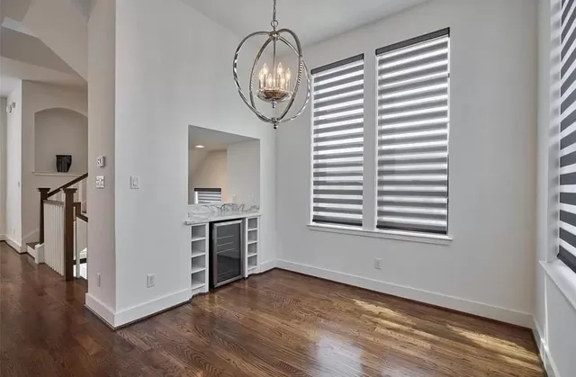 an empty room with wooden floor chandelier and windows