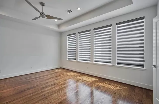 a view of an empty room with a window and wooden floor