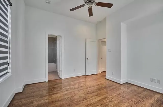 an empty room with wooden floor and ceiling fan