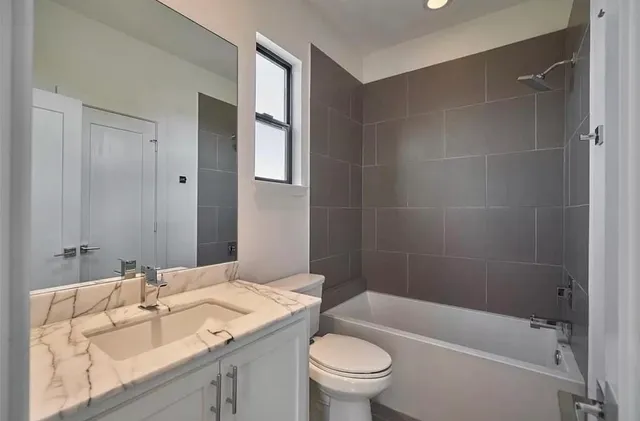 a bathroom with a granite countertop sink a toilet and shower