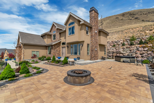 2543 East 700 South Springville, UT 84663 - Photo 3 of 73 Back of property featuring an outdoor fire pit, stucco siding, a chimney, stone siding, and a patio area