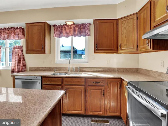a kitchen with kitchen island granite countertop wooden cabinets a sink and a stove