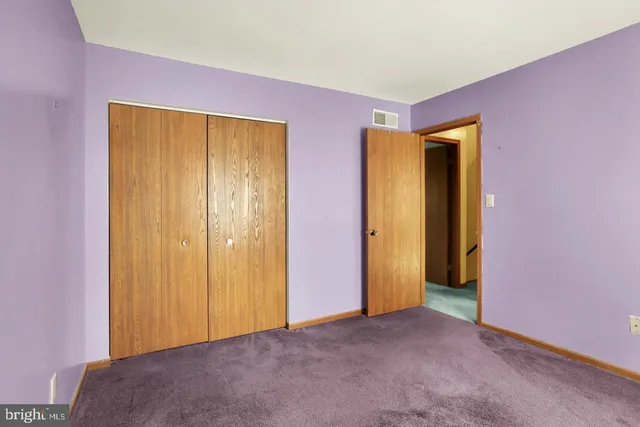 a view of an empty room with closet and a window