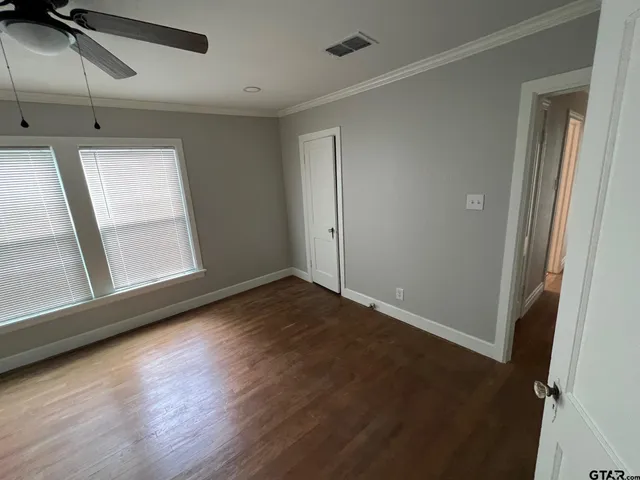 a view of empty room with wooden floor and fan