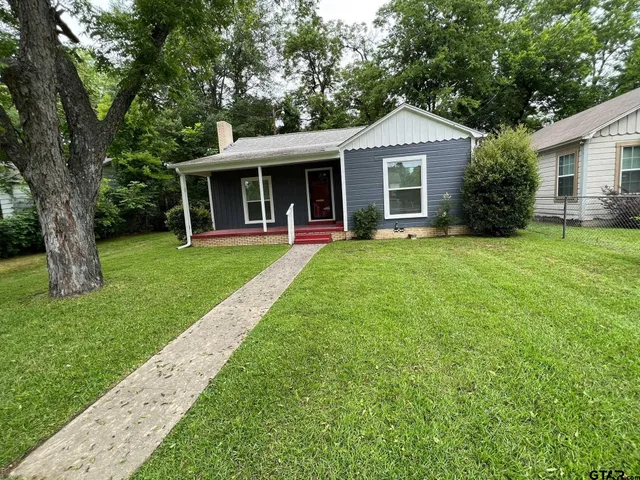 a front view of a house with a garden and trees
