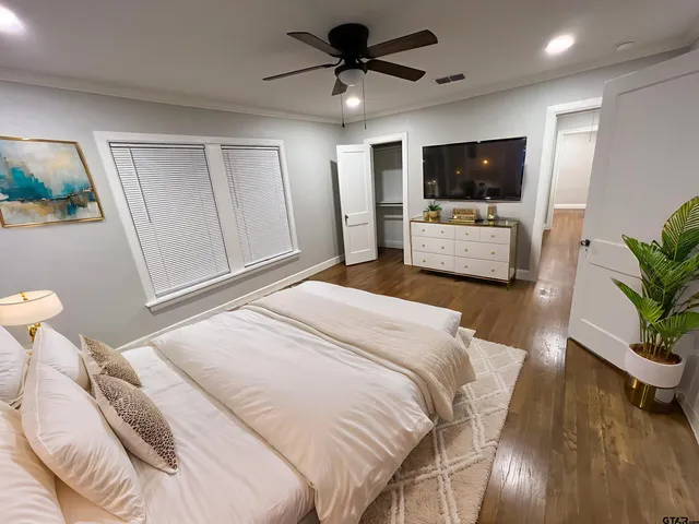 a bedroom with a bed a flat tv screen and a potted plant