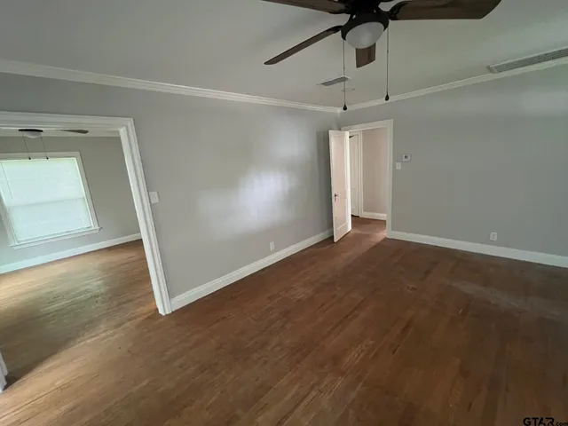 an empty room with wooden floor fan and windows