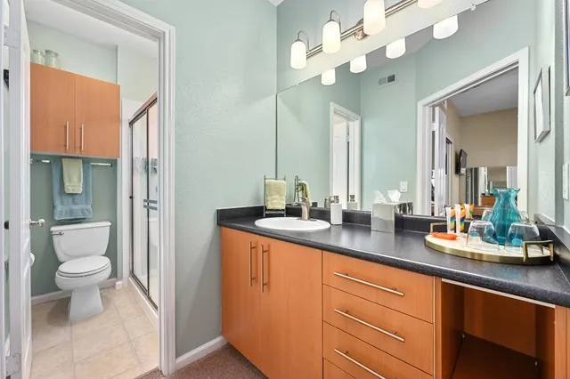 a spacious bathroom with a granite countertop sink a toilet and a mirror