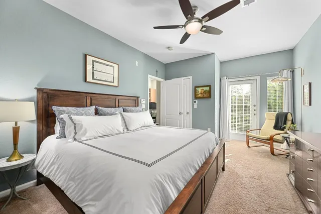 a bedroom with a large bed couch and two windows