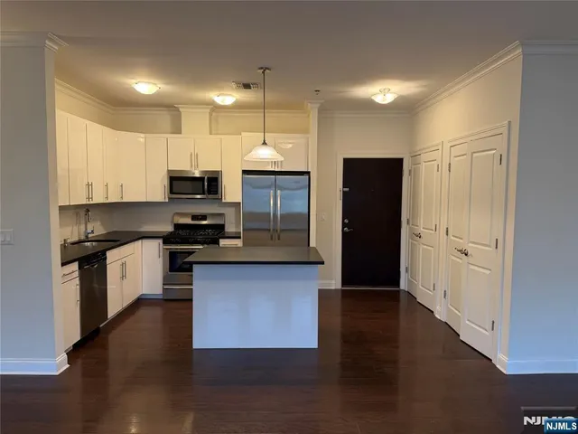 a kitchen with granite countertop a refrigerator and a stove top oven