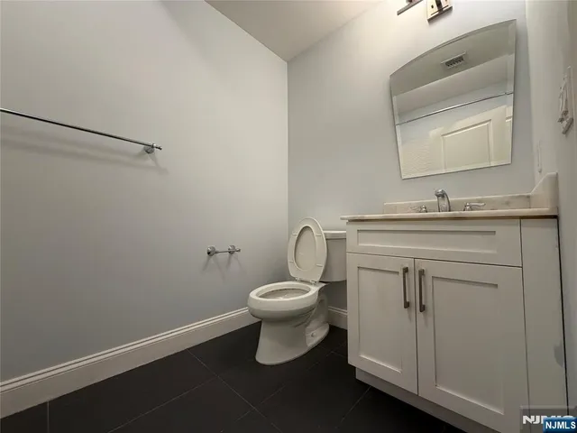 a bathroom with a toilet sink vanity and mirror