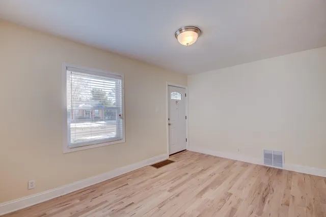 an empty room with wooden floor and windows