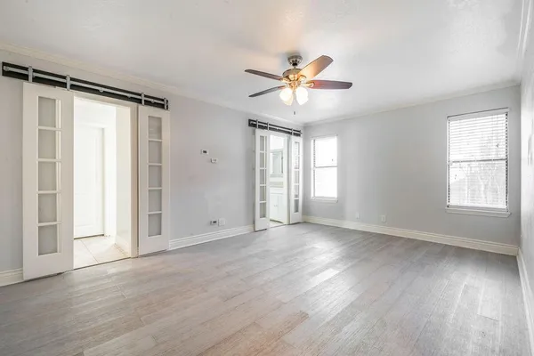 an empty room with wooden floor fan and windows