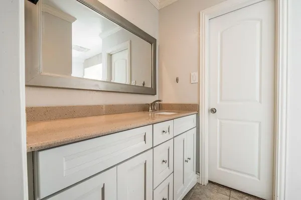 a view of a hallway with granite countertop white cabinets and a wooden floor