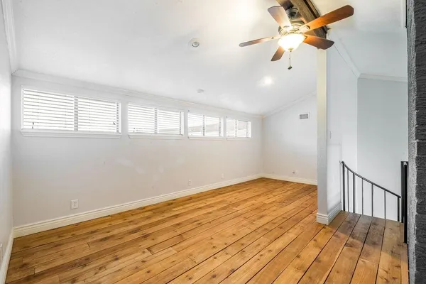 an empty room with wooden floor fan and windows