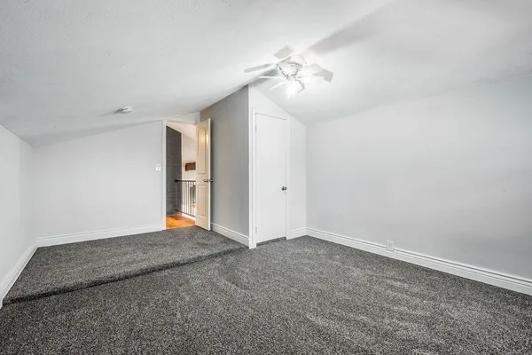 a view of an empty room with a chandelier fan