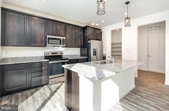 a kitchen with stainless steel appliances kitchen island granite countertop a sink stove and refrigerator