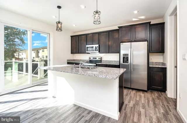 a kitchen with stainless steel appliances granite countertop a refrigerator a stove and a wooden floors