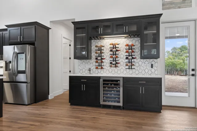 a kitchen with stainless steel appliances granite countertop a refrigerator and a wooden floor
