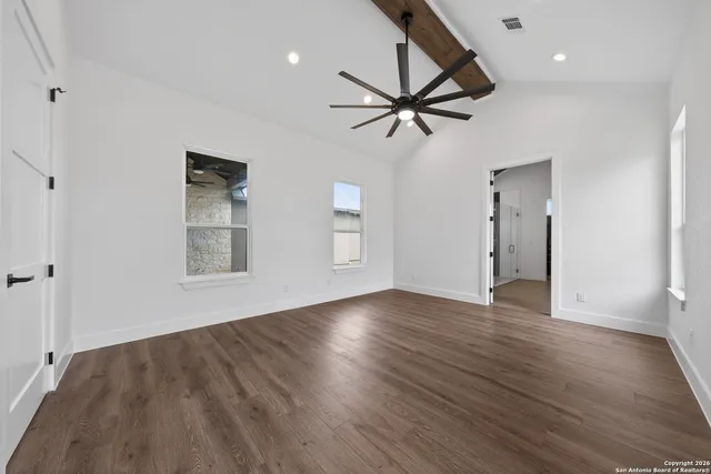 a view of empty room with wooden floor and fan