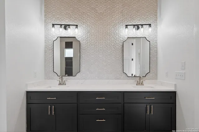 a bathroom with double vanity sinks and two mirror