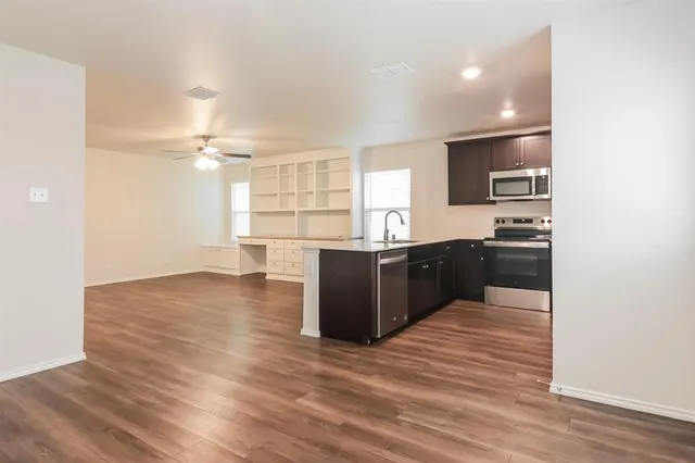 a kitchen with kitchen island a sink dishwasher a stove and a refrigerator with wooden floor