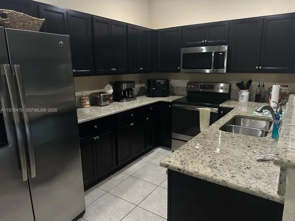a kitchen with a sink a microwave a refrigerator and cabinets