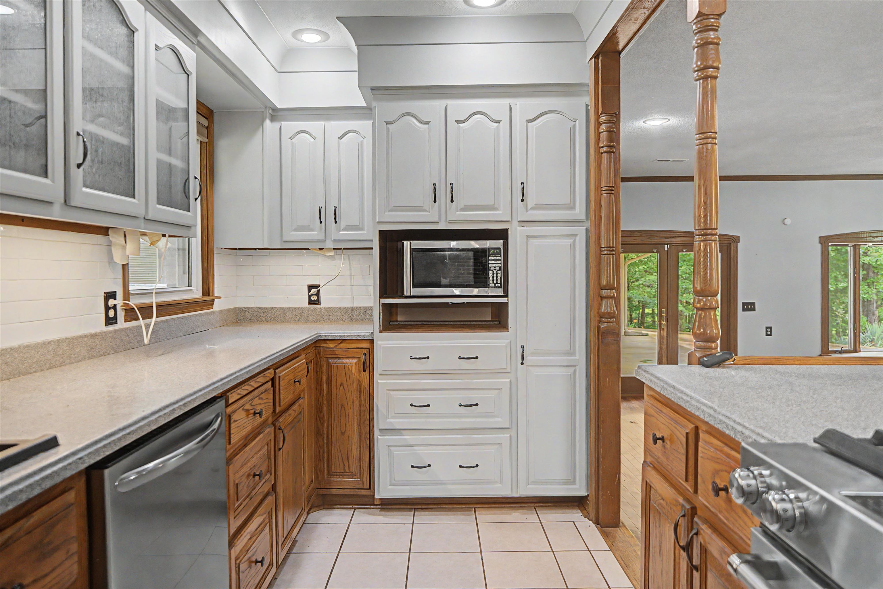 436 Skyline Road Selmer, TN 38375 - Photo 38 of 40 Kitchen featuring white upper cabinetry, wood-finish lower cabinetry, a built-in microwave, light-toned countertops, and white tile flooring