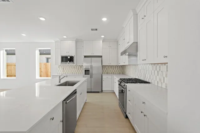 a kitchen with stainless steel appliances granite countertop a sink a stove and a refrigerator