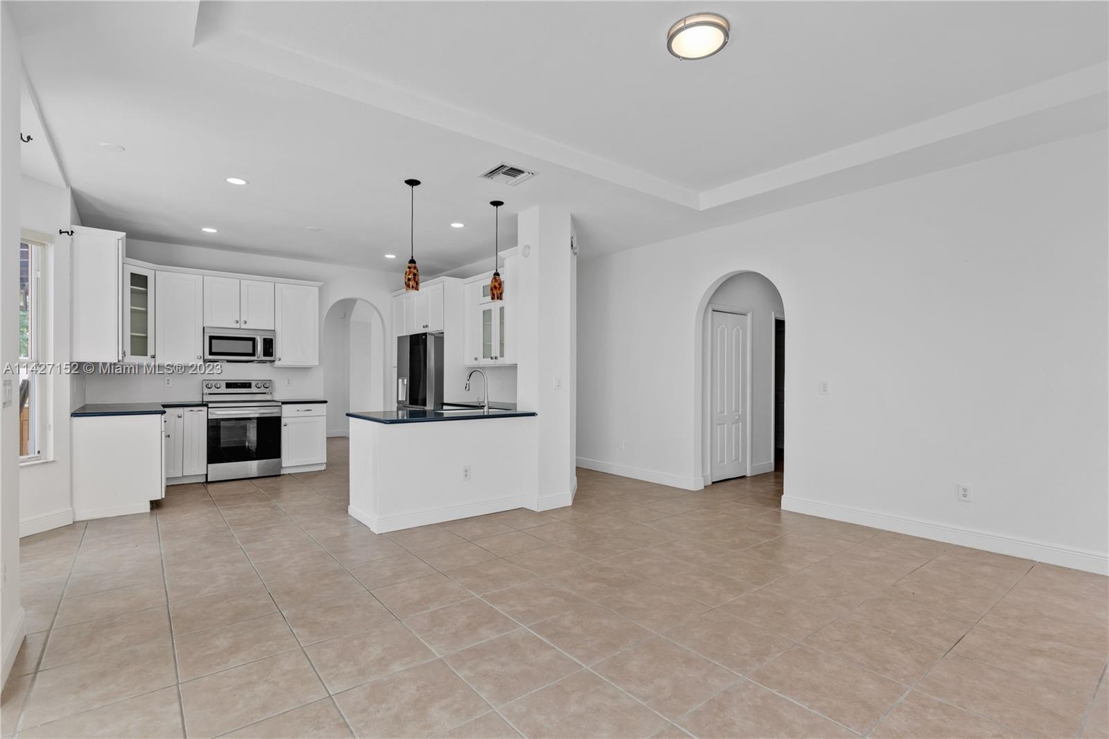 3759 Northeast 15th Street Homestead, FL 33033 - Photo 14 of 55 a large kitchen with stainless steel appliances kitchen island a white counter top and stove