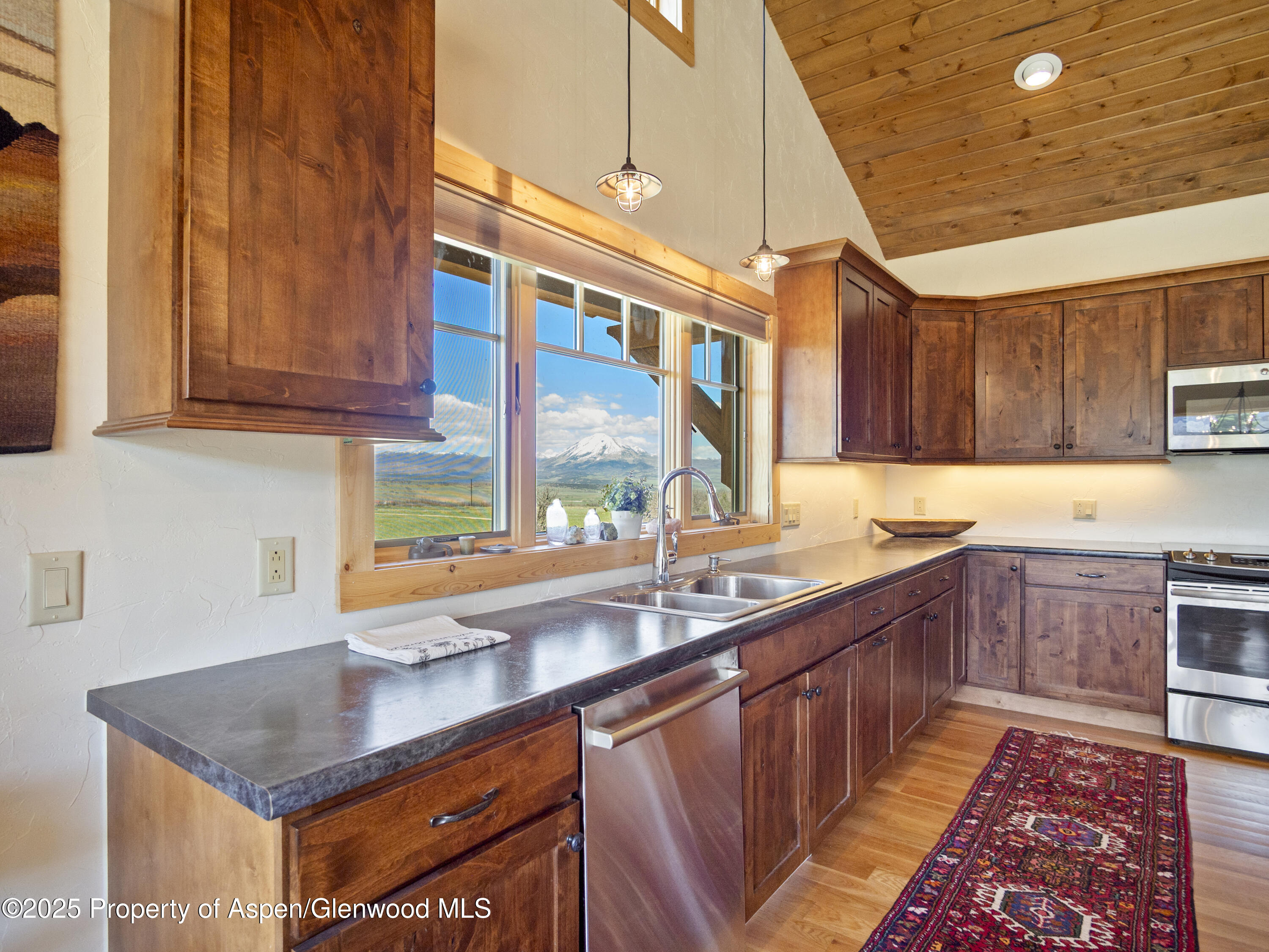 741 Big Wall Lane La Veta, CO 81055 - Photo 31 of 47 a kitchen with stainless steel appliances granite countertop a sink a stove and a wooden cabinets