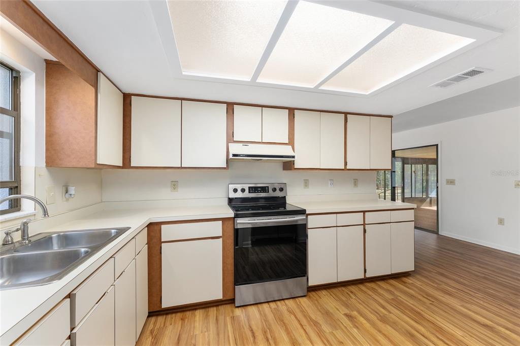 20290 Southwest 97th Place Dunnellon, FL 34431 - Photo 12 of 73 a kitchen with a sink cabinets wooden floor and stainless steel appliances