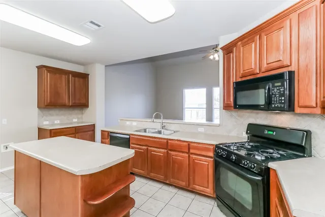 a kitchen with stainless steel appliances granite countertop a stove a sink dishwasher and a microwave oven with white cabinets