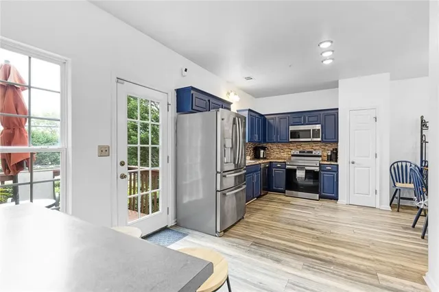 a kitchen with stainless steel appliances granite countertop a refrigerator stove a sink dishwasher and a stove with wooden floor