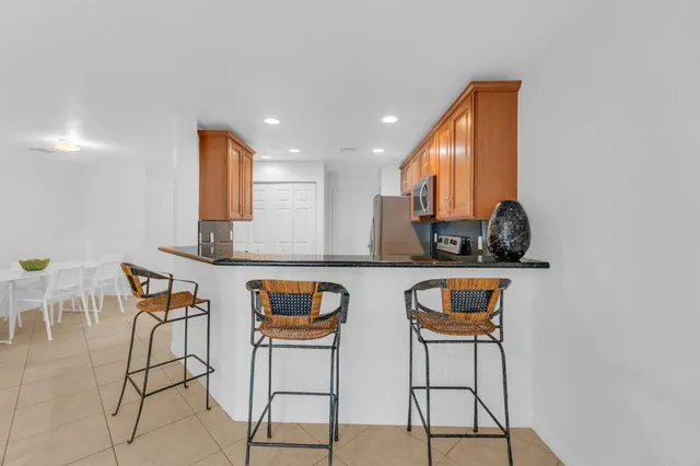 a kitchen with stainless steel appliances kitchen island granite countertop a table and chairs in it
