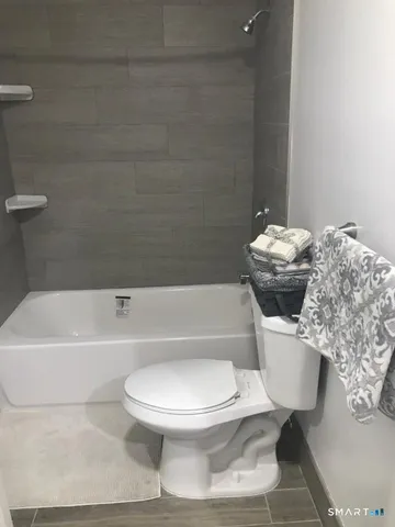 a white toilet sitting next to a white tub