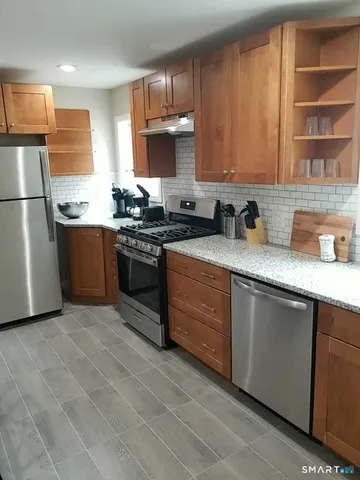 a kitchen with stainless steel appliances granite countertop a stove a sink dishwasher and a refrigerator