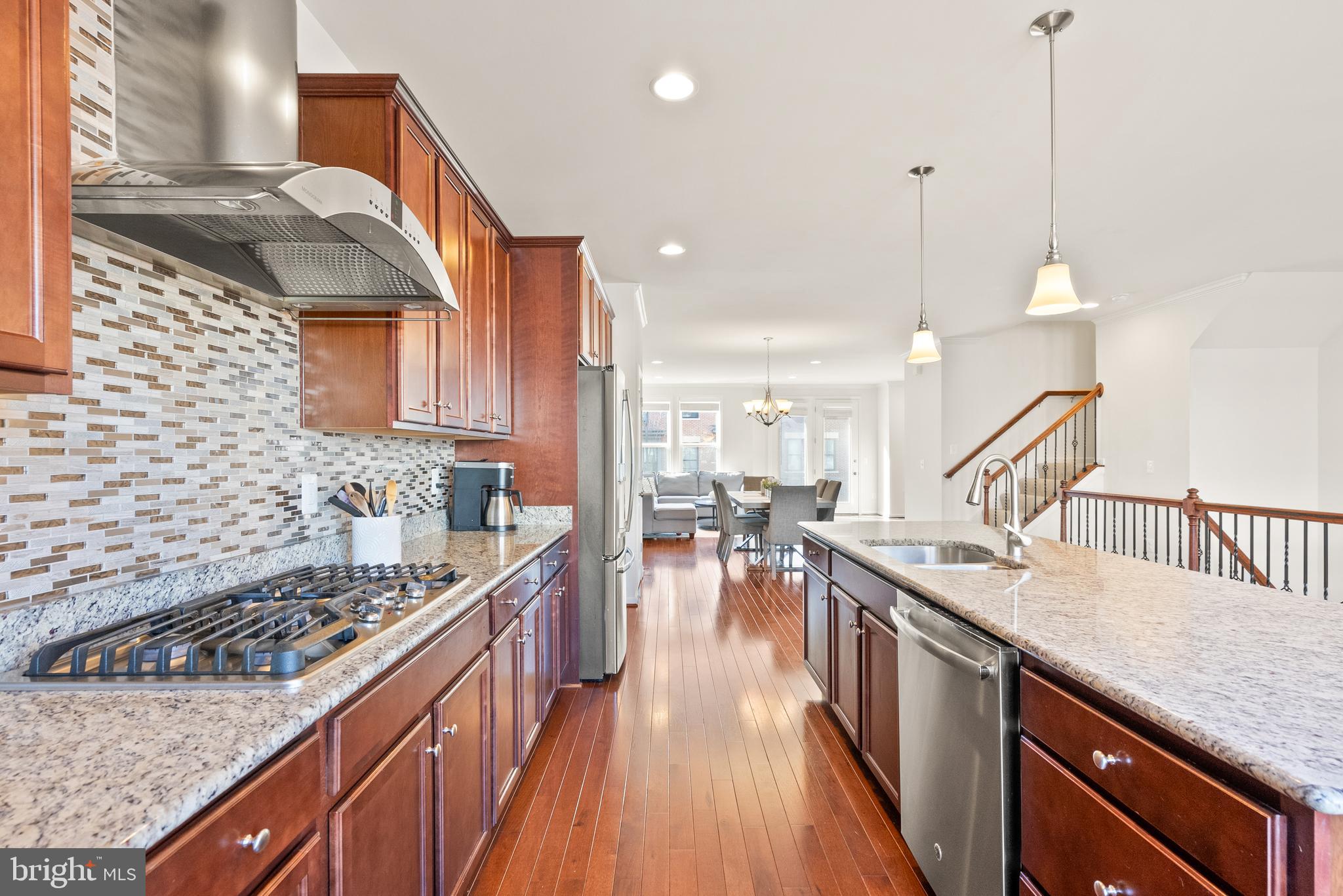 42274 Riggins Ridge Terrace Brambleton, VA 20148 - Photo 5 of 56 a kitchen with counter top space a sink a stove and wooden floors