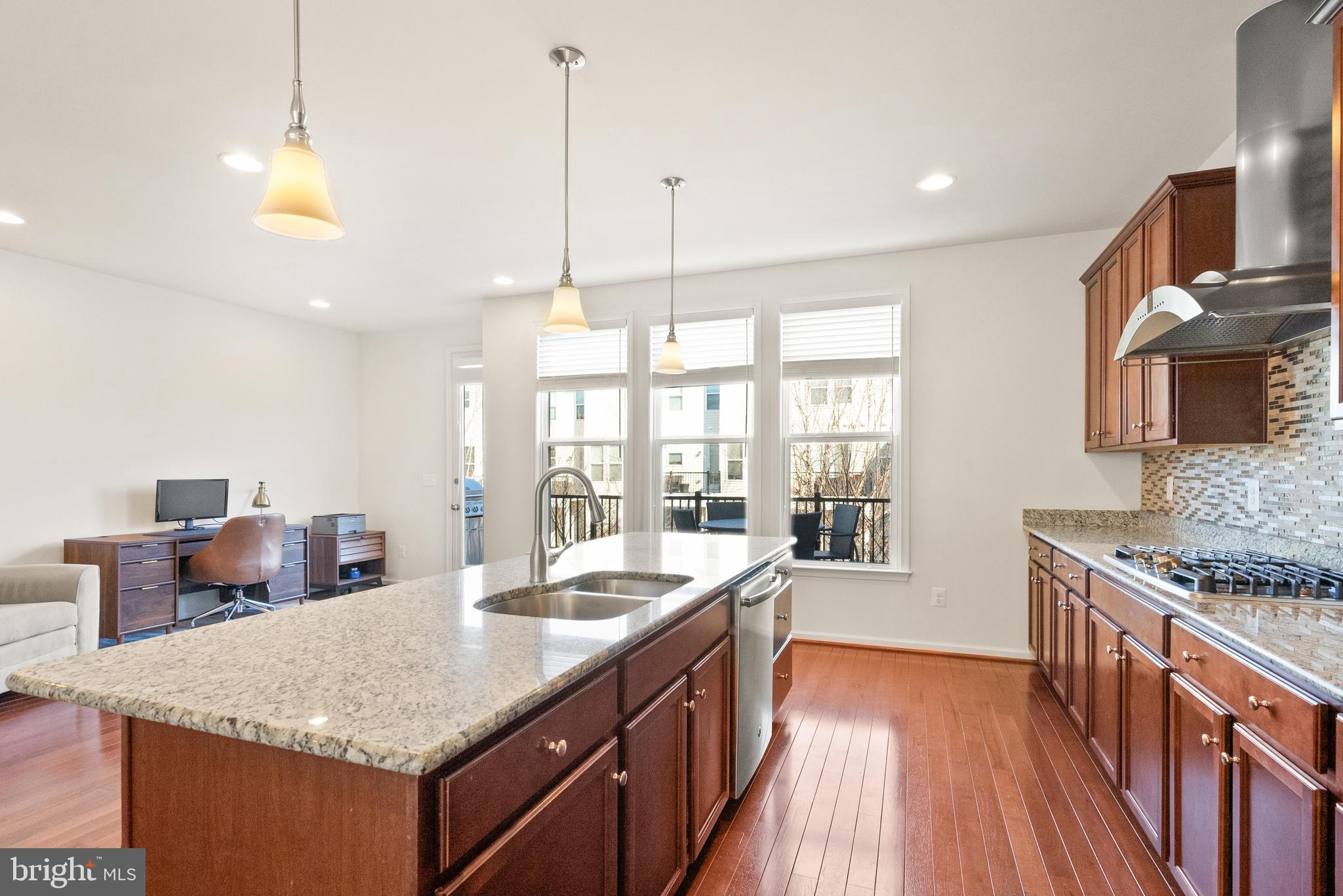 42274 Riggins Ridge Terrace Brambleton, VA 20148 - Photo 7 of 56 a kitchen with stainless steel appliances granite countertop a sink a stove and a wooden floor