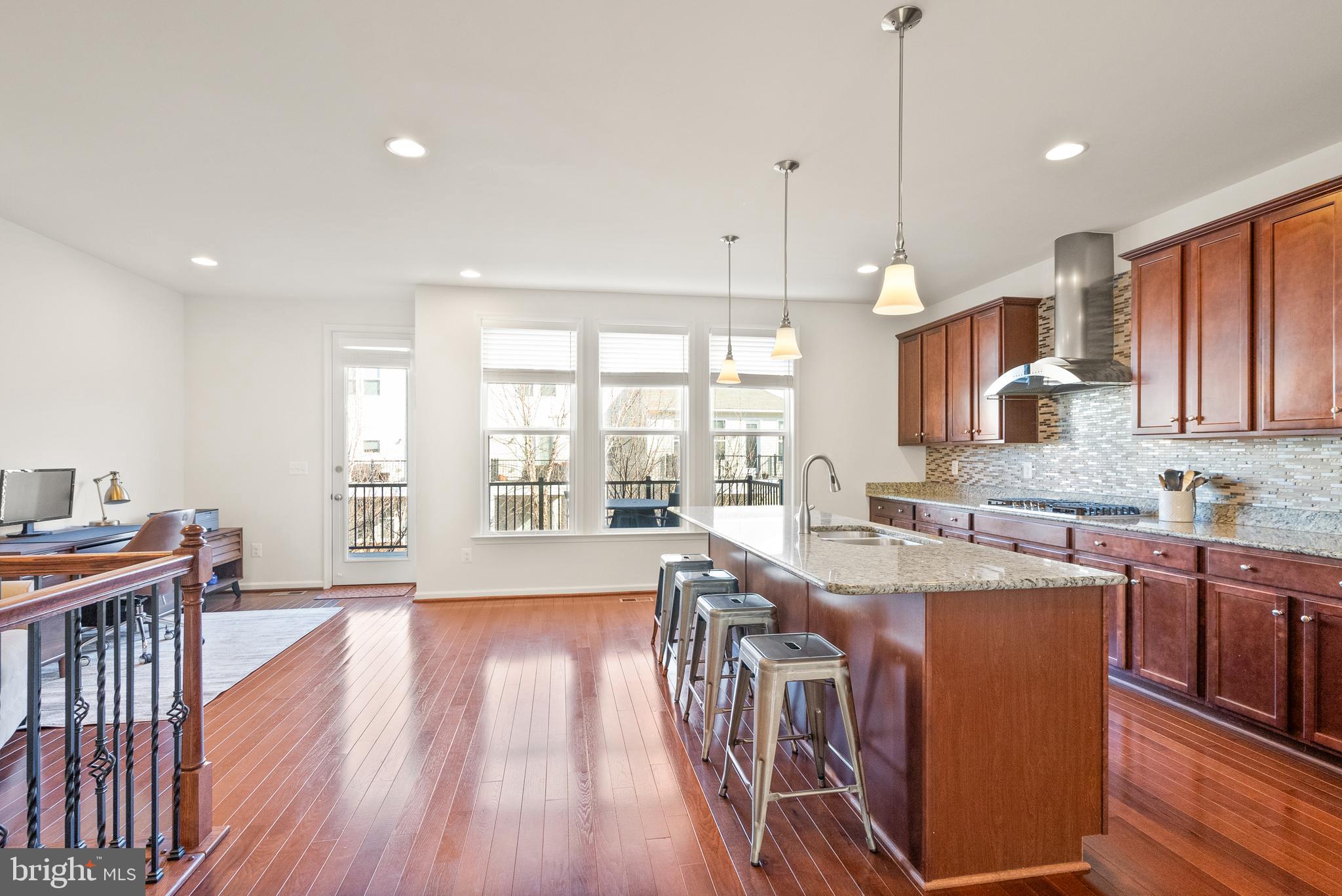 42274 Riggins Ridge Terrace Brambleton, VA 20148 - Photo 10 of 56 a kitchen with stainless steel appliances granite countertop a stove a refrigerator a kitchen island a sink and white cabinets with wooden floor