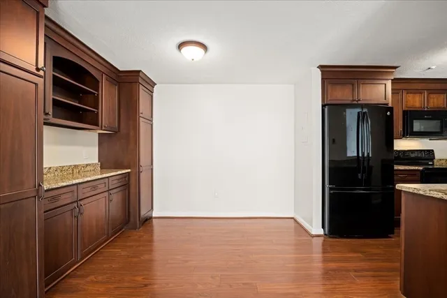 a kitchen with granite countertop a refrigerator stove and wooden floor