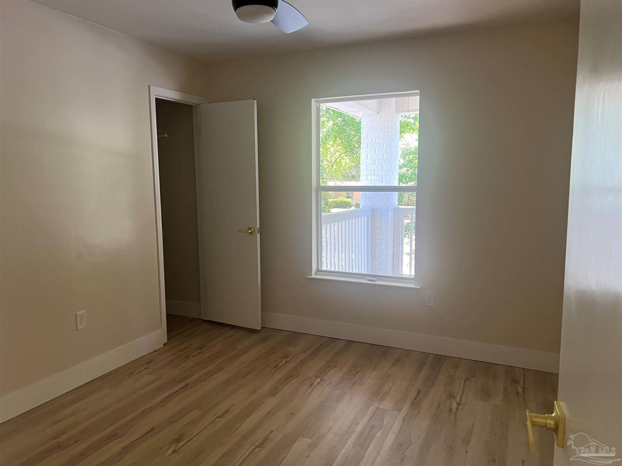 3111 Holley Point Road Navarre, FL 32566 - Photo 6 of 23 an empty room with wooden floor and windows