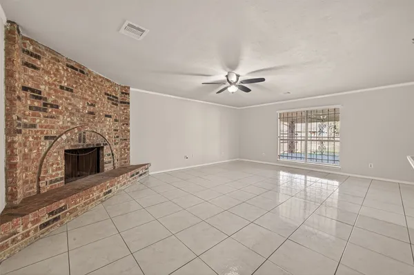a view of a livingroom with a fireplace a ceiling fan and windows