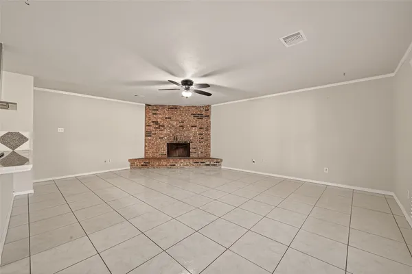 an empty room with fireplace and chandelier fan