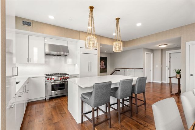 a kitchen with stainless steel appliances kitchen island granite countertop a stove a sink a dining table and chairs with wooden floor