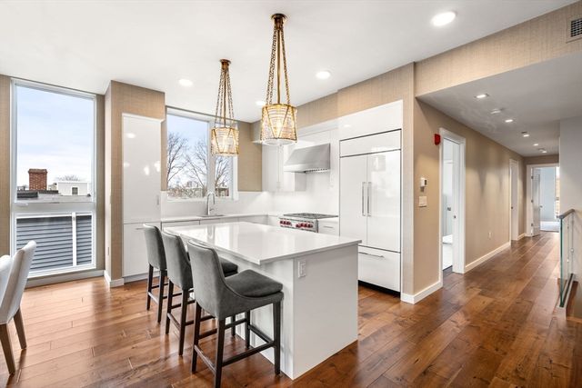 a kitchen with stainless steel appliances a dining table chairs and wooden floor