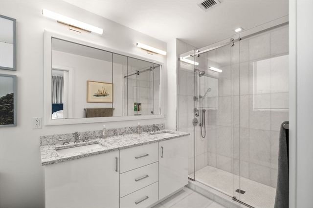 a bathroom with a granite countertop sink mirror and shower