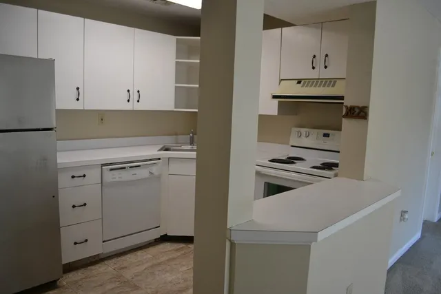 a kitchen with white cabinets and white appliances