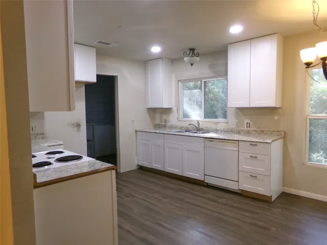 a kitchen with granite countertop white cabinets and refrigerator