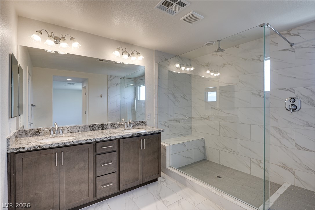 5954 Smith Valley Road Las Vegas, NV 89148 - Photo 15 of 23 A spacious primary bathroom boasts a dual-sink vanity and a grand walk-in shower with bench seating.